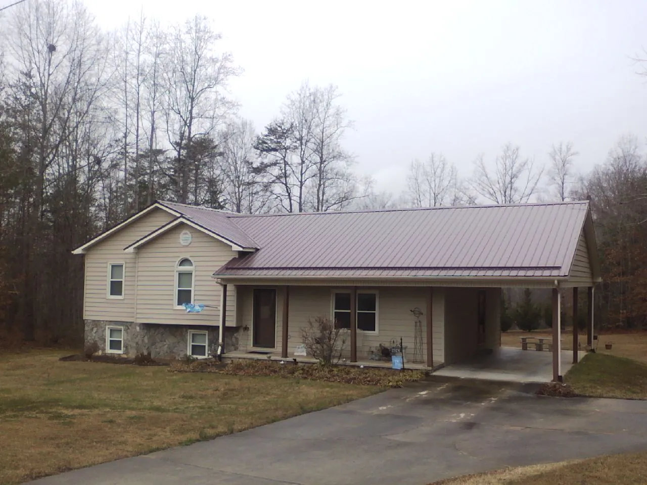 Burgundy metal roof on a tan split level home with an attached carport in Durango
