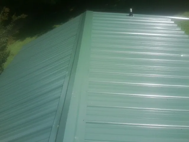 New green metal panels meeting at the ridge of a roof — Flat Roof Repair work by our crew in Durango