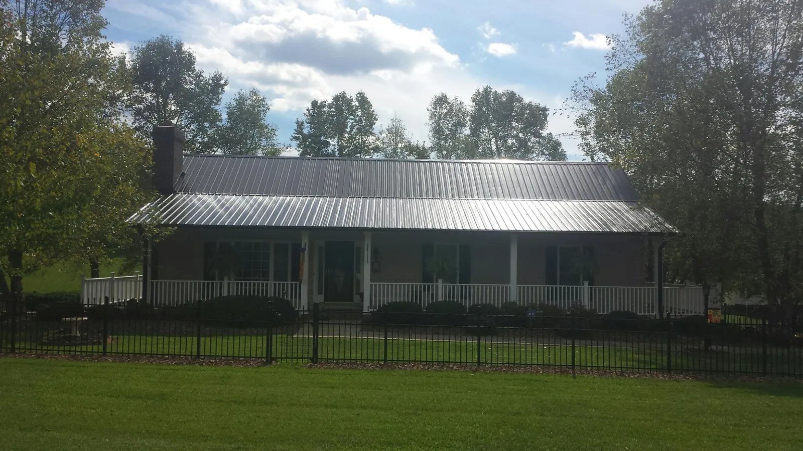 Gray metal roof on a brick ranch with a full width front porch — Gutter Guard Installation work by our crew in Durango