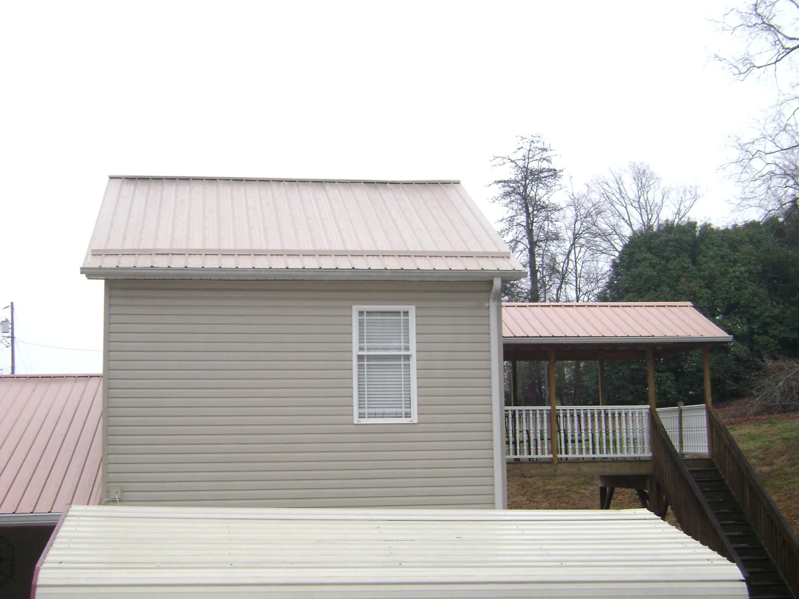 Tan metal roofs on a two story addition and attached porch, from a Roof Replacement job in Durango