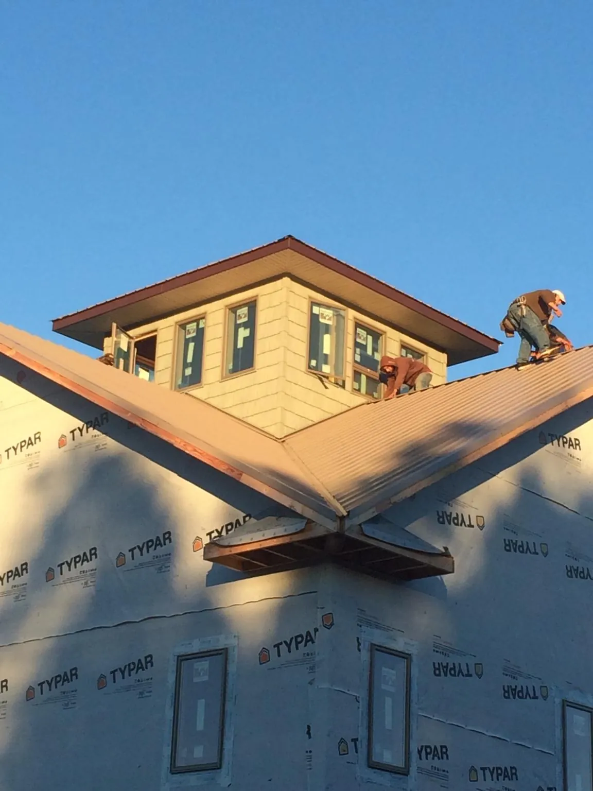 Roofers working around a rooftop cupola on a new metal roof at sunset — Roof Waterproofing in Durango by Roofing Brothers